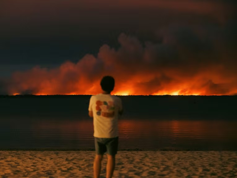 Depuis le bassin d'Arcachon, les habitants et les vacanciers observent, stupéfaits, l’incendie qui fait rage de l’autre côté du lac, à Biscarrosse, et qui s’est déclenché seulement quelques heures plus tôt, le jeudi 23 juillet 2026. HANS LUCAS VIA AFP/LAURENT PERPIGNA IBAN